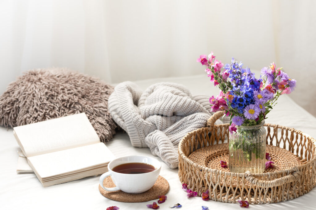 Cup of tea, a bouquet of wildflowers, book and knitted element.